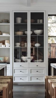 a kitchen with lots of white cabinets and wooden flooring, along with wicker baskets on the countertops