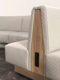 the back end of a white couch with wood trimmings and an arm rest