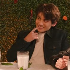 a young man sitting at a table with a glass of milk in front of him