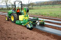 a green tractor is driving down the road