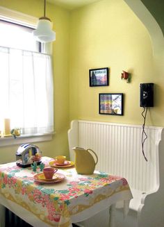 a table with a plate and cups on it in front of a wall mounted phone