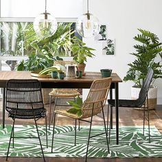 a dining room table with chairs and plants