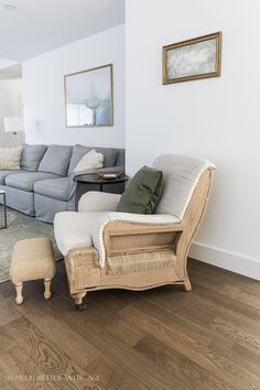 a living room with white walls and wood flooring, couches and chairs are arranged around a coffee table