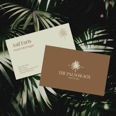 two business cards sitting on top of palm trees in the dark, one is brown and white