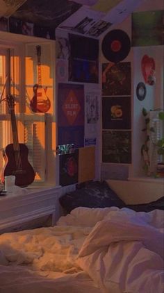 a bedroom with an electric guitar hanging from the ceiling next to a bed and window