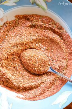 a spoon is in a bowl filled with ground spices and seasoning on the side