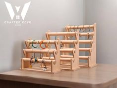 two wooden racks holding rings and bracelets on top of a table next to a wall