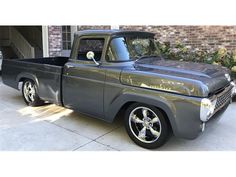 an old gray truck parked in front of a brick building next to a garage door