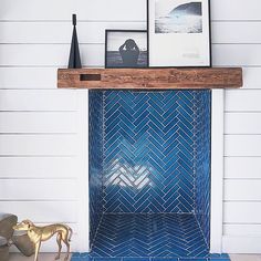 a blue tiled fireplace with two pictures on the mantle