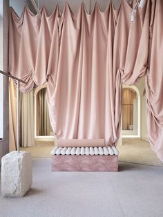 a room with pink drapes and white balls on the floor next to a stone block