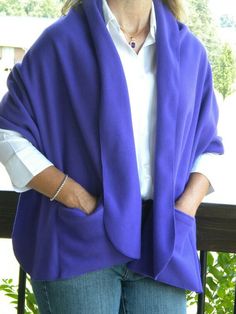 a woman wearing a purple shawl standing on a balcony with her hands in her pockets