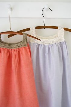 two dresses hanging on a wooden hanger