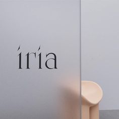 a white chair sitting next to a wall with the word aria written on it