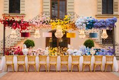 a table set up with chairs and flowers on the tables in front of a building