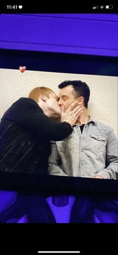 a man and woman kissing each other in front of a purple screen with the words love on it