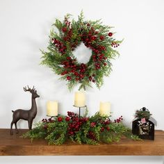 a christmas wreath and candles on a mantel with deer figurines next to it