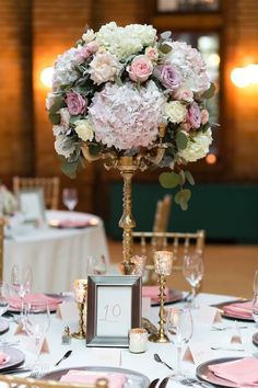 a centerpiece with pink and white flowers sits on top of a table