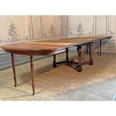 a large wooden table sitting on top of a hard wood floor next to a wall