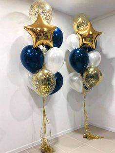 two large balloons with gold and white stars are on the floor in front of a wall