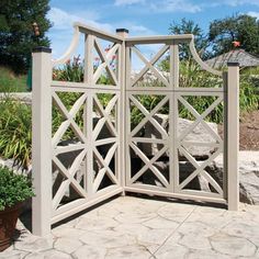 a white wooden gate sitting on top of a stone patio next to potted plants