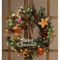 a christmas wreath hanging on a door with lights and decorations around it that says merry christmas