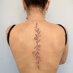 the back of a woman's neck with a flower tattoo on her left side