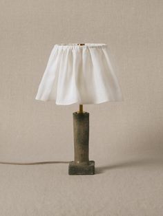 a table lamp with a white shade on it's base and a cord plugged in