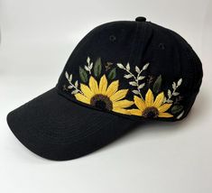 a black hat with yellow sunflowers embroidered on the front and side, against a white background