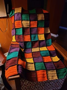 a multicolored crocheted blanket sitting on top of a chair