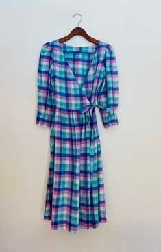 Vintage madras check wrap dress size 4. Fit and flare with A-line skirt bottom hitting below the knee. V neckline and capulet sleeve. Sleeves are 3/4 length with pleated effect at cuff. Fabric ties at waist that weave through insert holes to wrap and tie for closure. Two side insert pockets. Brand is Mati Sport. Believe it to be from the late 70s/early 80s. Measures 43.5 inches length and 17 in from underarm to underarm. 100% cotton. Made in India. Dress Clothes For Women, A Line Skirt, A Line Skirts, Fit And Flare, Wrap Dress, Art Collection, Dress Outfits, Bathing Beauties, Size 4