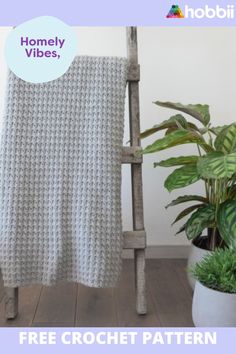 a crocheted blanket sitting on top of a wooden chair next to a potted plant