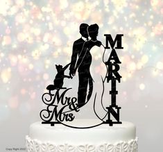 a wedding cake topper with the silhouette of a bride and groom holding a dog