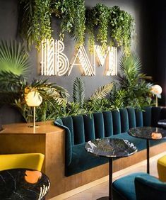 the interior of a restaurant with green plants on the wall and blue velvet seating area