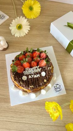 a birthday cake with chocolate frosting and strawberries on top, surrounded by flowers