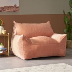 a living room with a pink chair and potted plant on the side table next to it