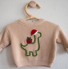 Happy Holidays! A-Roarable baby/toddler Christmas dinosaur sweaters custom hand embroidered by me, with a little help from my toddler (aka her just trying to steal my yarn). Dino sweaters come embroidered with the design as shown in pictures OR I can always custom make something else and alter it however you would like! I can change the sweater color, yarn colors, or even the design! (think Christmas trees, name in Christmas lights, wreaths, candy canes ... I would love to be creative for you!) I'd love to work with you and can send you examples before I start embroidering, so we can make the perfect Holiday sweater for your little one!   Knit dino sweaters in dark or light khaki.. or message for other sweater colors :) Knit sweaters come a bit large, for an oversized fit on your babe. If Boy Embroidered Sweater, Embroidery Sweater Ideas, Diy Christmas Sweater Ideas, Christmas Sweater Embroidery, Hand Embroidery Sweater, Toddler Christmas Sweater, Dinosaur Christmas Sweater, Toddler Ugly Christmas Sweater, Embroidered Christmas Sweater