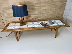 a wooden table with a magazine on it next to a lamp