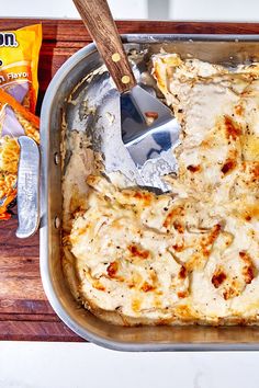 a casserole dish with meat and cheese in it next to a bag of chips