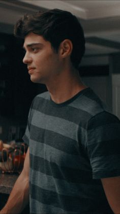 a young man standing in front of a counter with drinks on it and looking off to the side