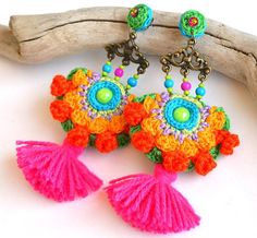 colorful crochet earrings with tassels and beads hanging from them on a branch