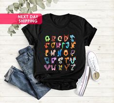 Alphabet Shirt, ABC Shirt, Alphabet With Animal T-Shirt, Alphabet Shirt For Teachers, Kindergarten Teacher Tee, Gift for Teacher, TeacherTee Hi!  Welcome to the Goshirtly! It's great to see you here! BLACK TEXT is used for Yellow, Heather Peach, White, Athlethic Heather, Light Blue, Mint, Pink Shirts. Other colored shirts have white text. F I T ∙ & ∙ S I Z I N G : -->Women's sizes are narrower than the waist -->Sleeves are rolled up in some product pictures. They do not come rolled up on deliver Multicolor Cartoon Print T-shirt For School, Multicolor Letter Print Shirt For Streetwear, Casual Multicolor Tops With Name Print, Multicolor Crew Neck T-shirt With Name Print, Multicolor Graphic Tee With Name Print, Casual Multicolor Shirt With Name Print, Black T-shirt With Sublimation Print For School, Multicolor Graphic Tee Shirt With Name Print, Casual Multicolor T-shirt For School