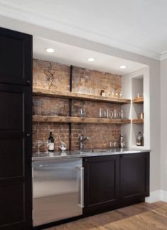 a kitchen with brick wall and stainless steel sink, dishwasher and wine rack