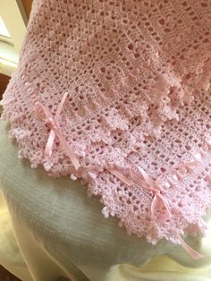 a pink crocheted shawl on top of a table