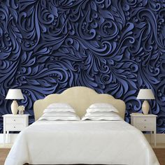 a bed sitting in front of a blue wall with swirly designs on the headboard