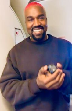 a smiling man holding a remote control in his right hand and looking at the camera