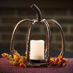 a white candle sitting on top of a table next to a decorative pumpkin shaped decoration