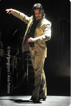 a man standing on top of a stage with his arms out and one hand in the air