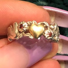 a gold ring with a heart on the front and two hearts on the back, sitting in someone's hand