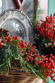 red berries and pine cones in a wicker basket on a table with other christmas decorations