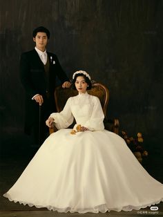 a man and woman in formal wear posing for a photo on a chair with an umbrella